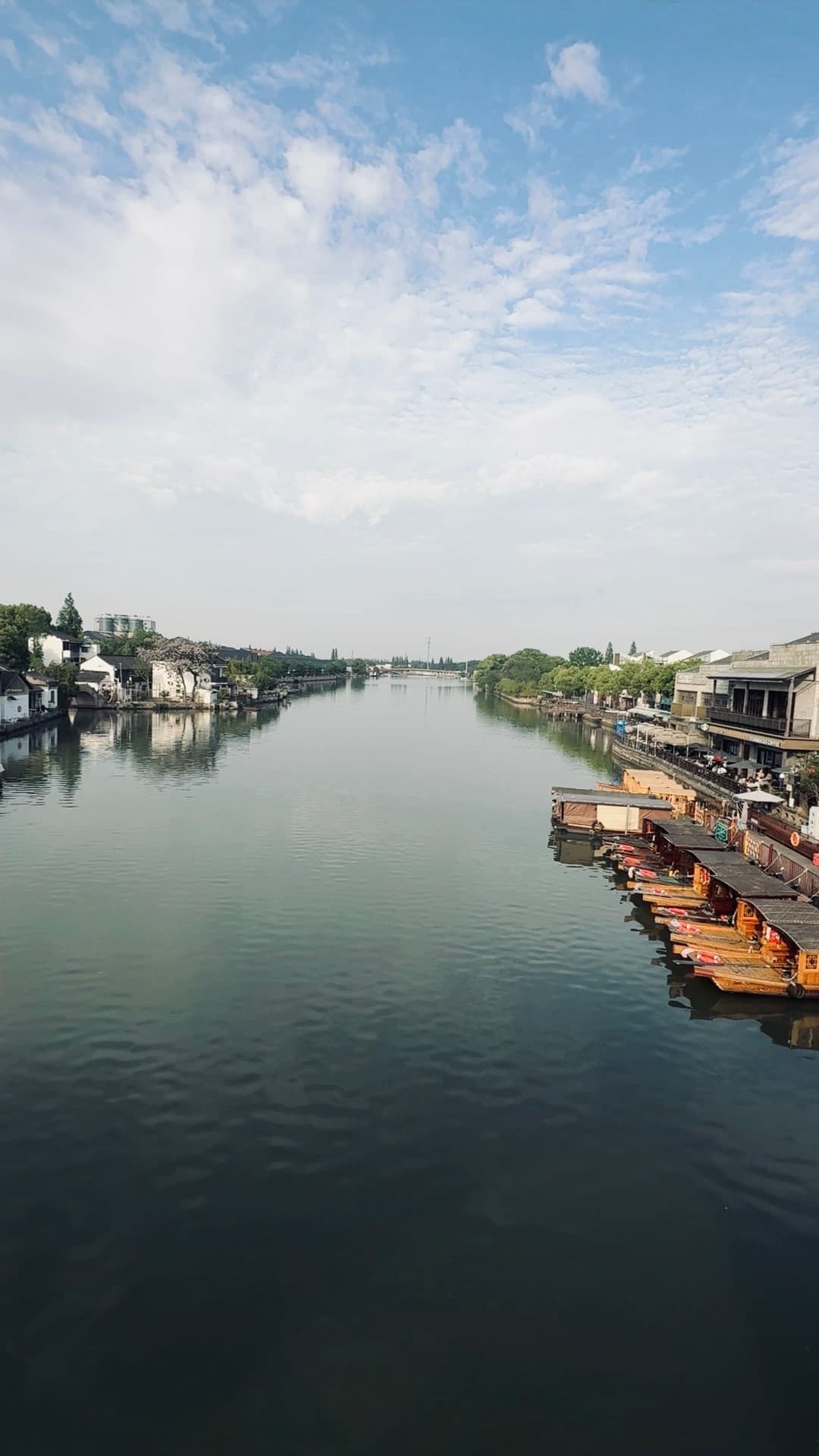 Traditional wooden boats docked along a calm river in a scenic historic water town.